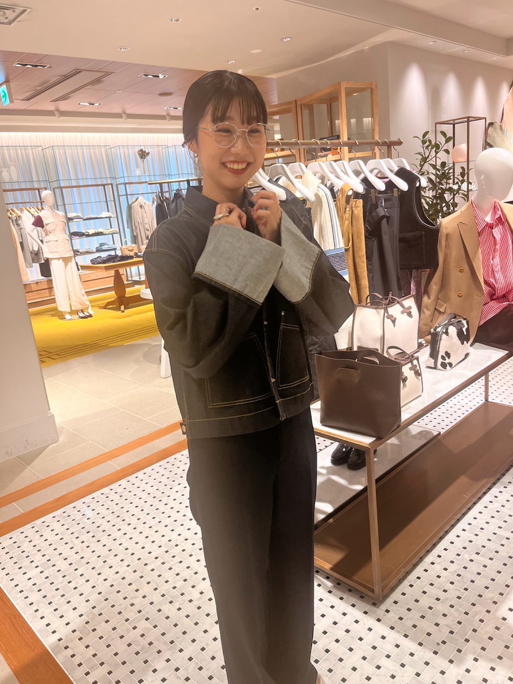 ブルー系のスラックス、ホワイト系のサンダル、ブラウン系のハンドバッグを着用したレディースの秋コーディネートの2枚目の写真