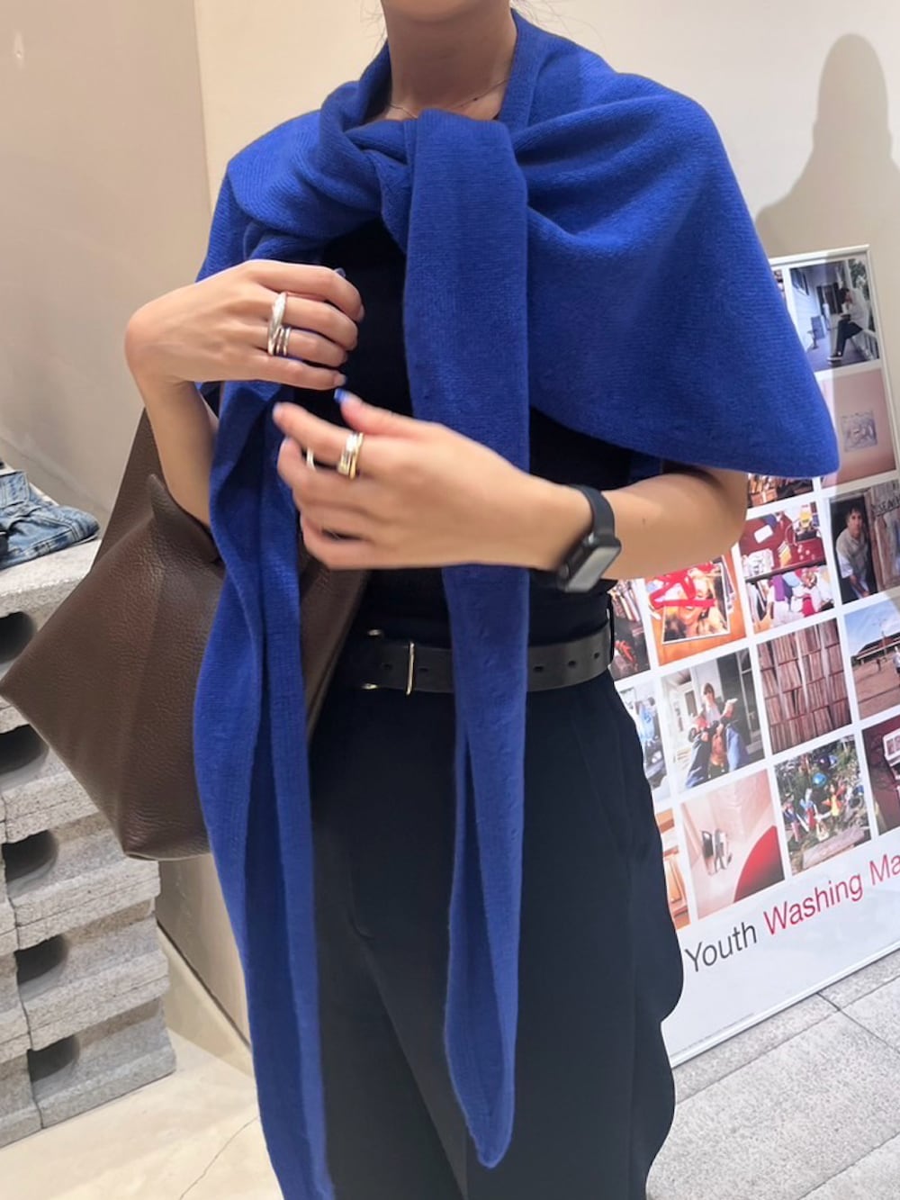 ブルー系のスラックス、ホワイト系のサンダル、ブラウン系のハンドバッグを着用したレディースの秋コーディネートの3枚目の写真