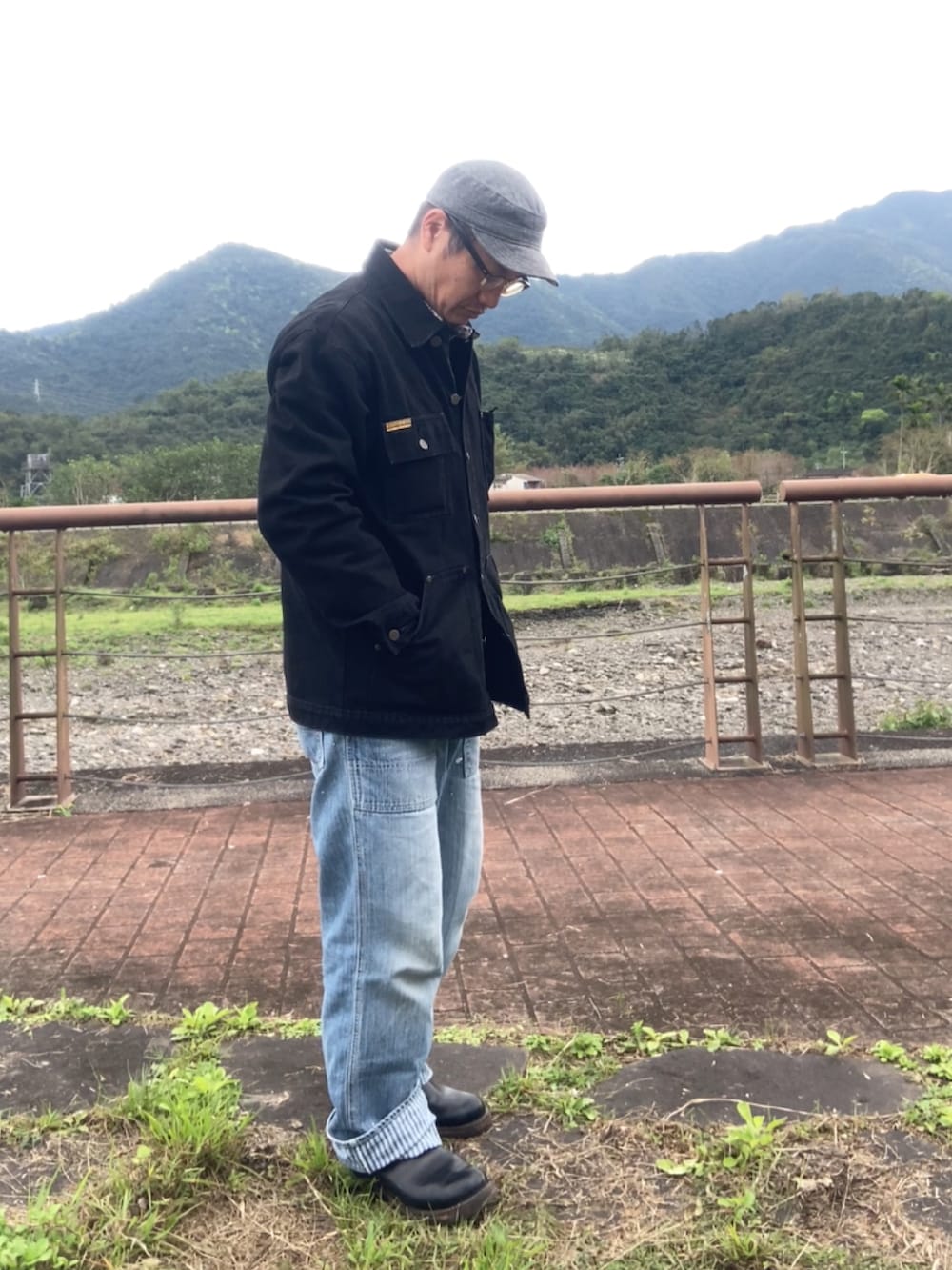 ブラック系のカバーオール、ブルー系のデニムパンツ、ブラック系のブーツを着用したメンズの冬コーディネートの2枚目の写真