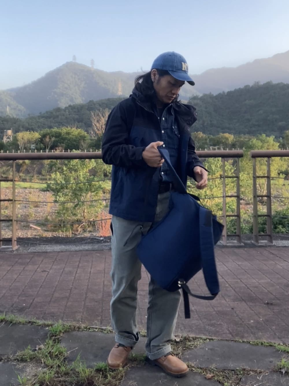 ブルー系のバックパック/リュック、ブラック系のマウンテンパーカー、グリーン系のその他パンツを着用したメンズの冬コーディネートの2枚目の写真