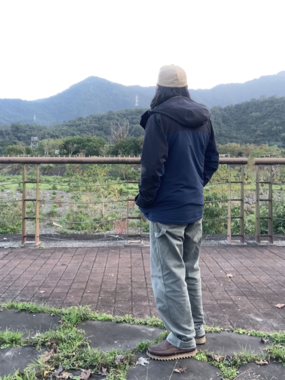 ブラウン系のブーツ、ブラック系のマウンテンパーカー、ブラウン系のベストを着用したメンズの冬コーディネートの3枚目の写真