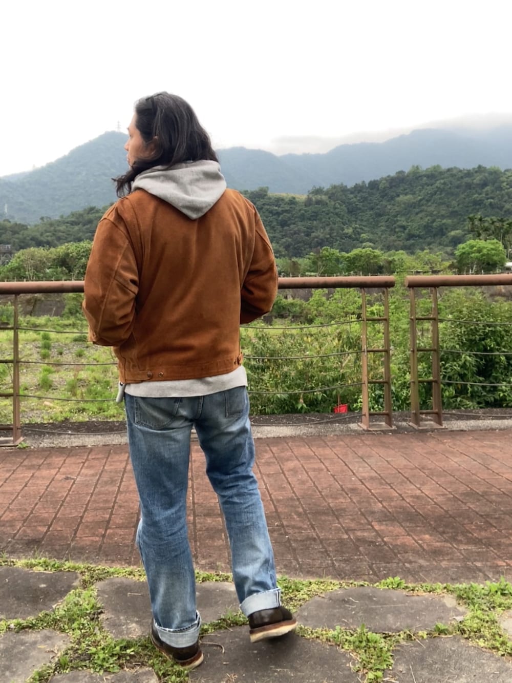 ブラウン系のその他アウター、ブルー系のデニムパンツ、ブラック系のブーツを着用したメンズの春コーディネートの5枚目の写真