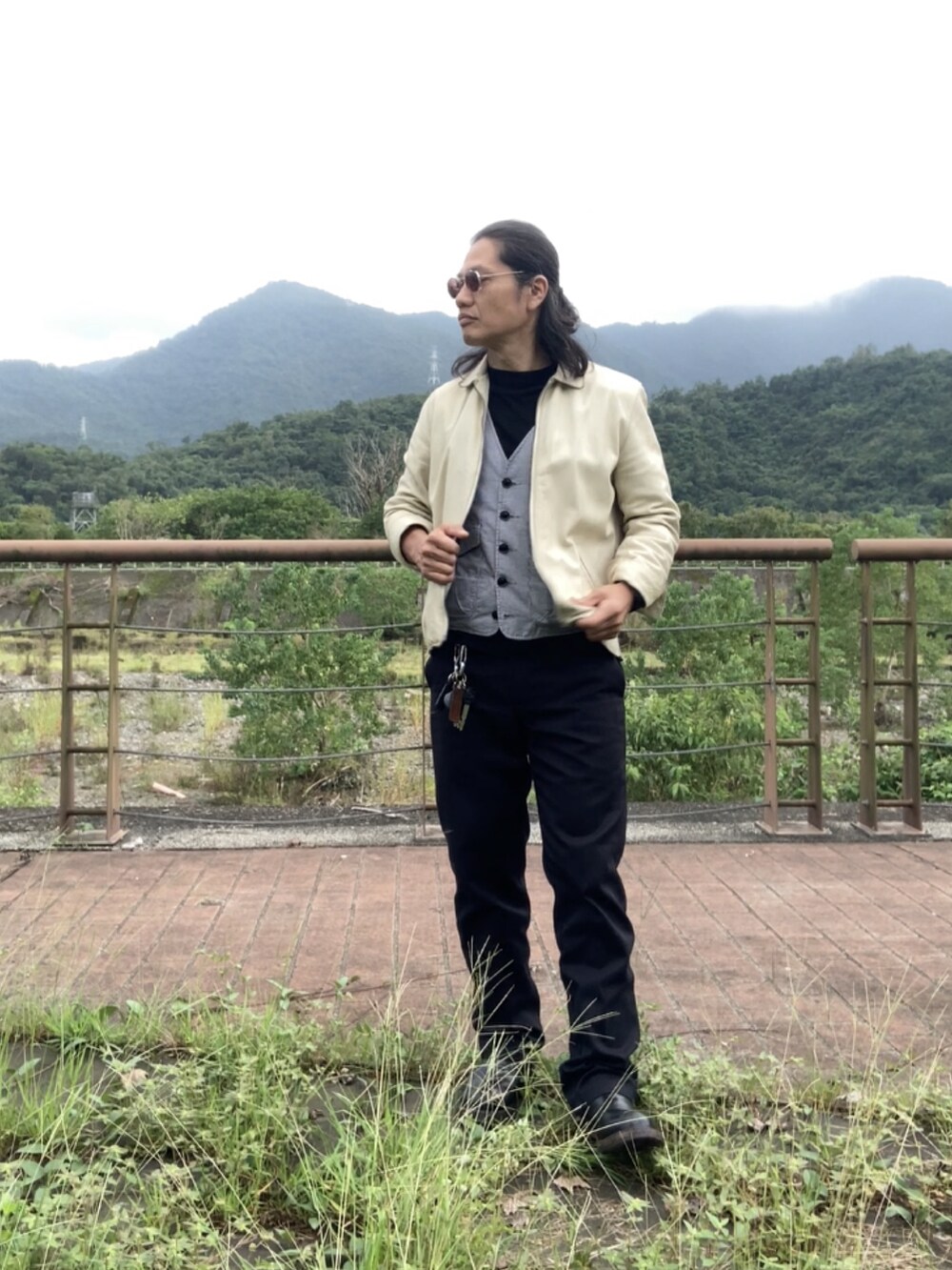 ホワイト系のブルゾン、グレー系のベスト、ブラック系のチノパンツを着用したメンズの秋コーディネートの3枚目の写真