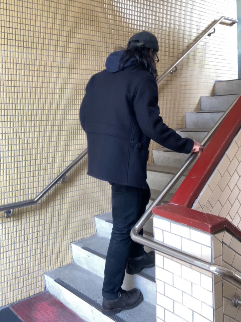 ブルー系のパーカー、ブラック系のブーツ、ブラック系のデニムパンツを着用したメンズの春コーディネートの2枚目の写真
