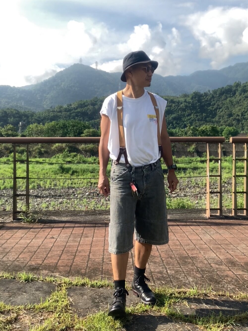 ホワイト系のTシャツ/カットソー、ブラック系のデニムパンツ、ブラック系のブーツを着用したメンズの夏コーディネートの3枚目の写真