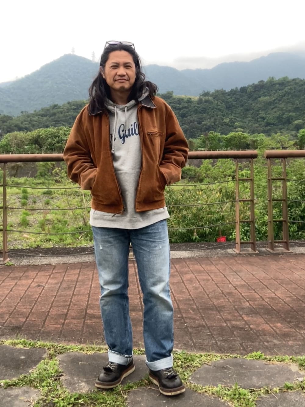 ブラウン系のその他アウター、ブルー系のデニムパンツ、ブラック系のブーツを着用したメンズの春コーディネートの4枚目の写真