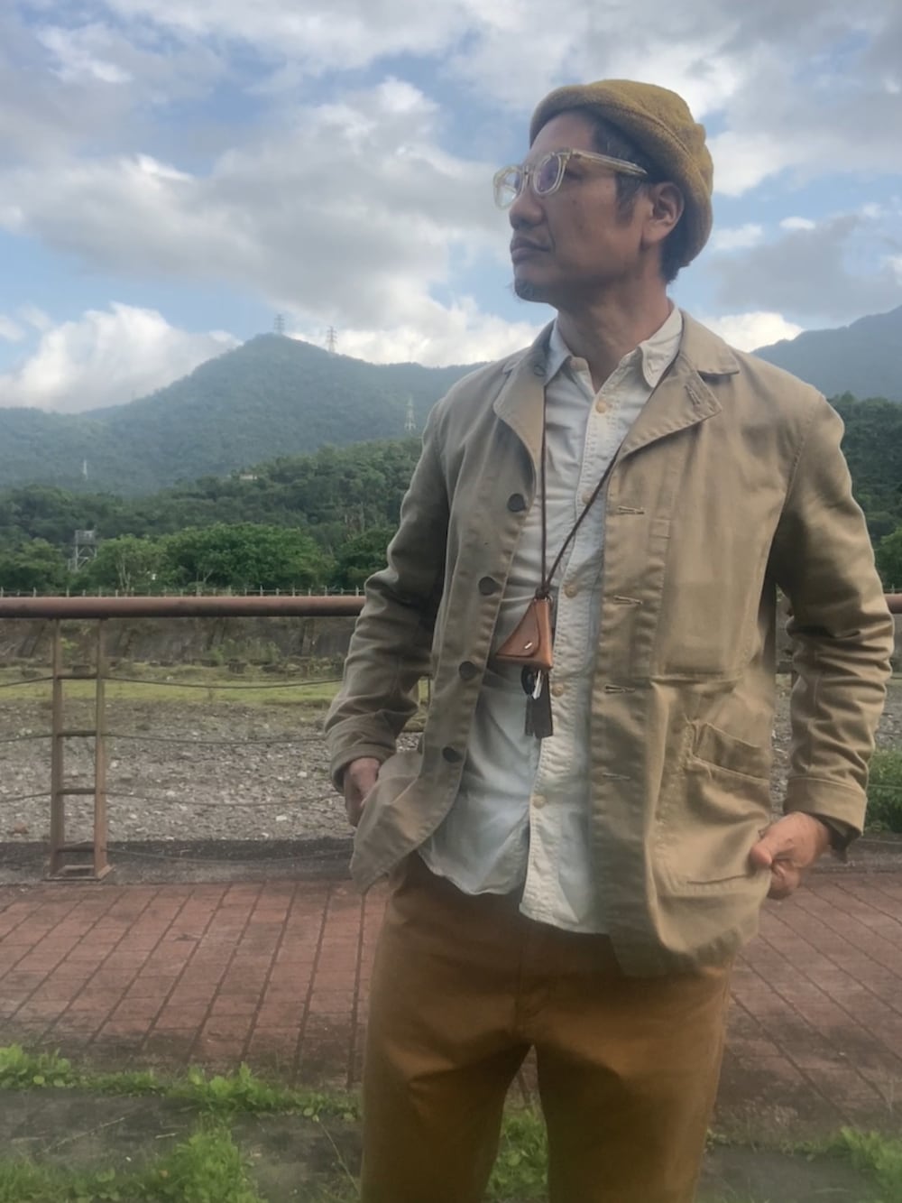 ベージュ系のカバーオール、ブラウン系のチノパンツ、ブラウン系のブーツを着用したメンズの春コーディネートの4枚目の写真