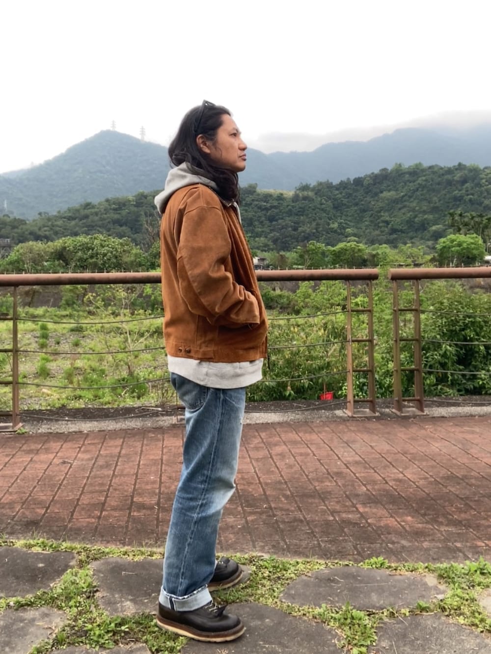 ブラウン系のその他アウター、ブルー系のデニムパンツ、ブラック系のブーツを着用したメンズの春コーディネートの3枚目の写真