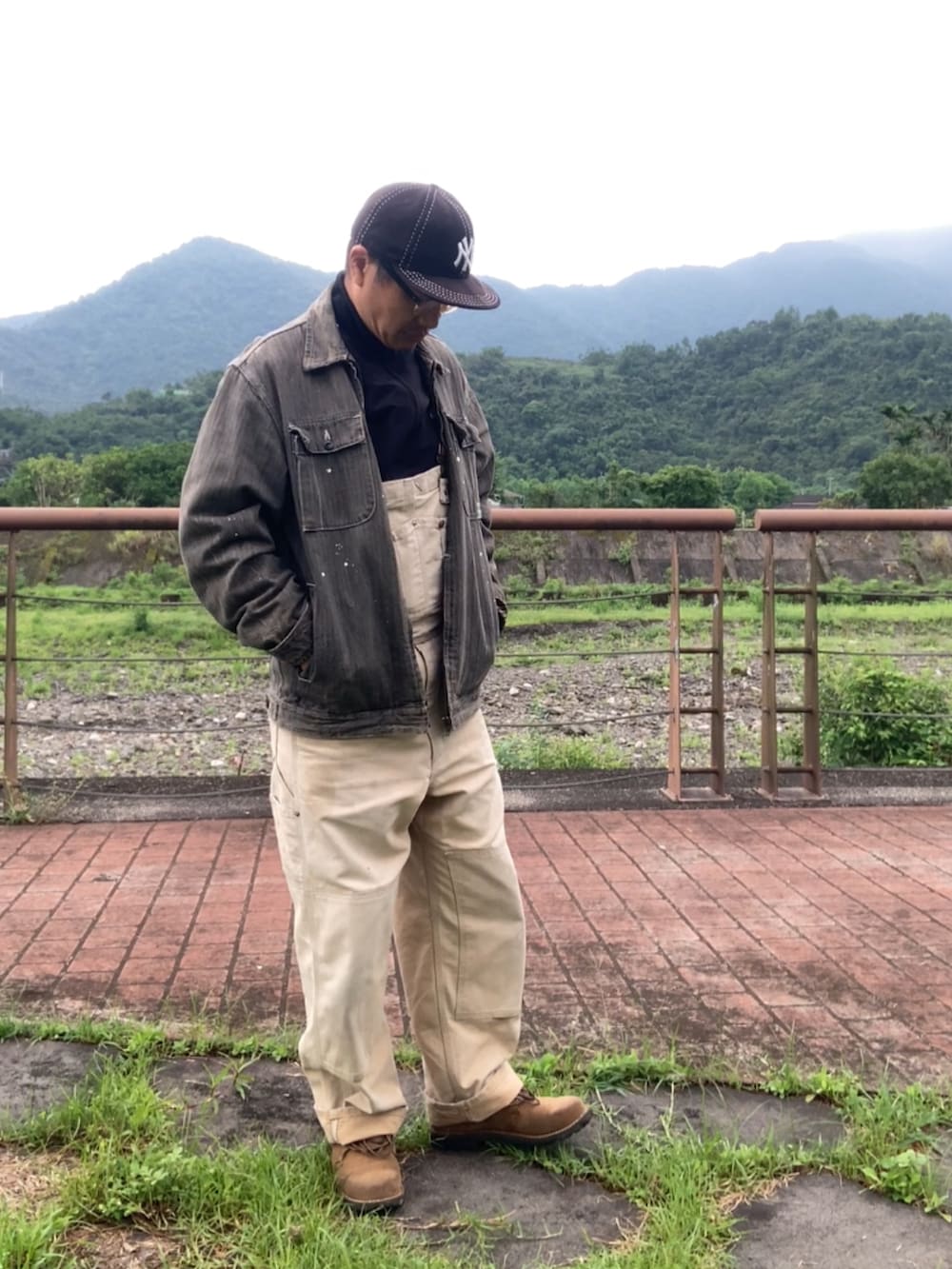 ブラウン系のサロペット/オーバーオール、ブラック系のジャージ、ブラウン系のブーツを着用したメンズの春コーディネートの3枚目の写真