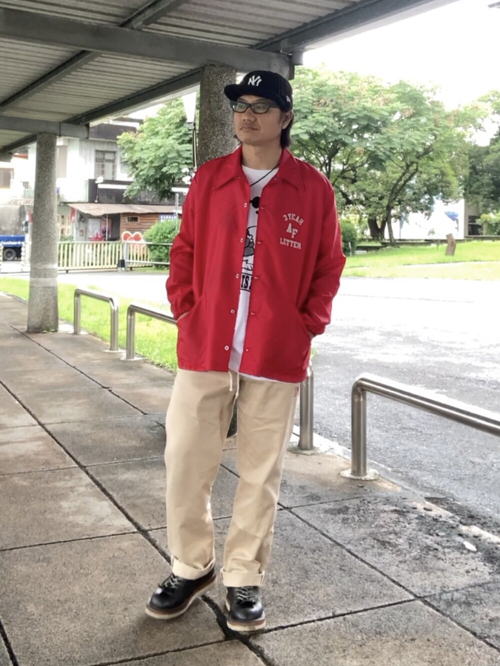 ホワイト系のTシャツ/カットソー、ベージュ系のチノパンツ、ブラック系のブーツを着用したメンズの夏コーディネートの3枚目の写真