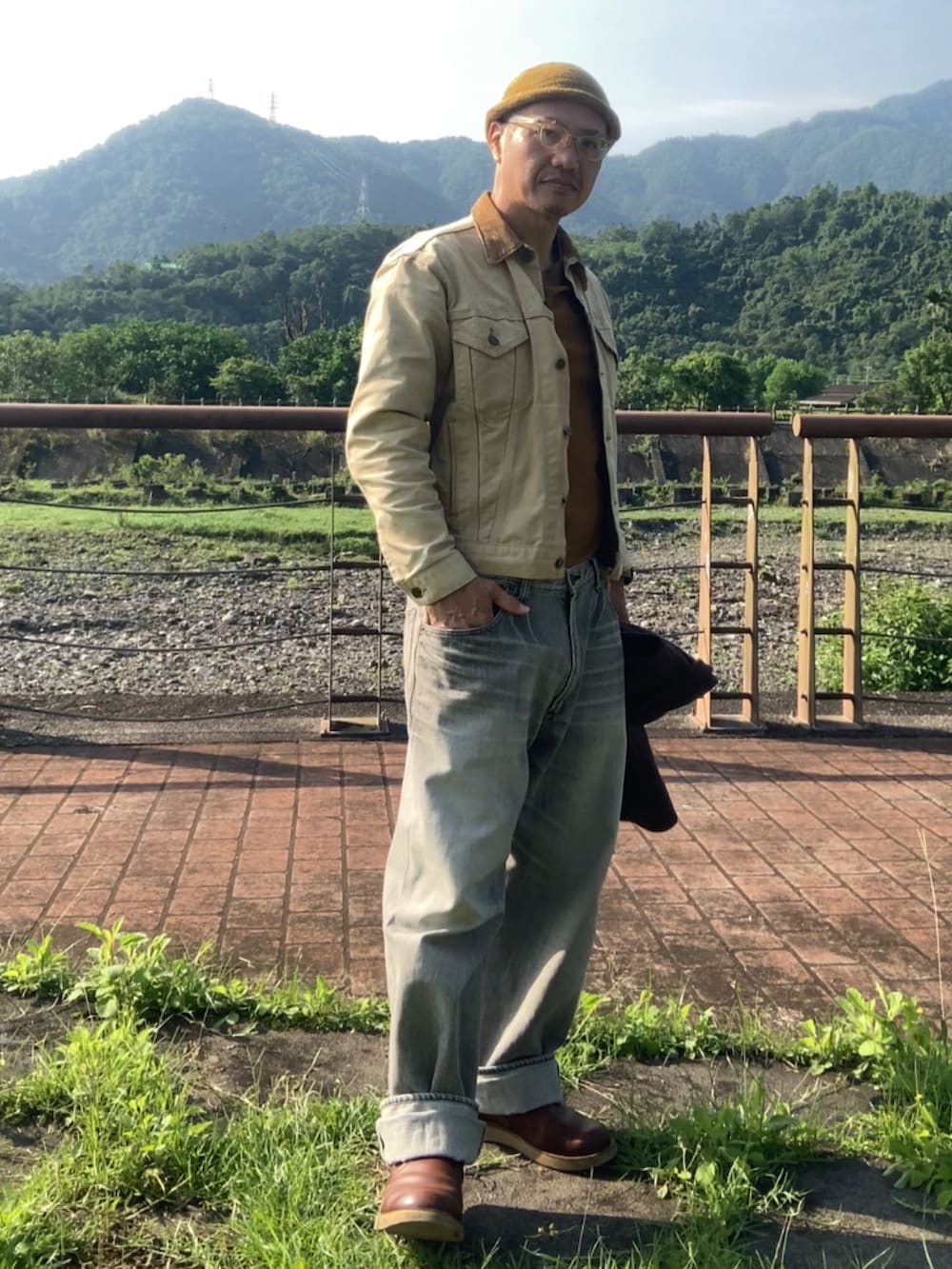 ベージュ系のデニムジャケット、ブラウン系のスリッポン、レッド系のその他アウターを着用したメンズの春コーディネートの2枚目の写真