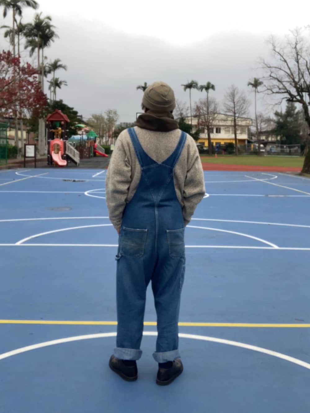 ベージュ系のニット/セーター、ブルー系のサロペット/オーバーオール、ブラック系のシューズを着用したメンズの冬コーディネートの2枚目の写真