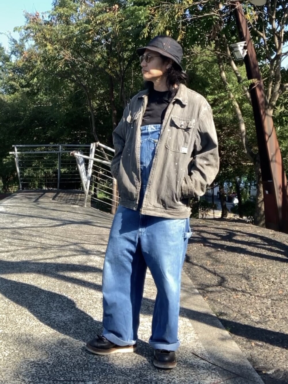 ブルー系のサロペット/オーバーオール、ブラック系のブーツ、ブラック系のデニムジャケットを着用したメンズの秋コーディネートの3枚目の写真