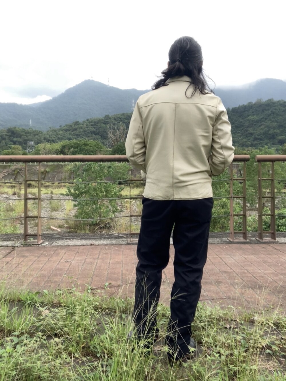 ホワイト系のブルゾン、グレー系のベスト、ブラック系のチノパンツを着用したメンズの秋コーディネートの2枚目の写真