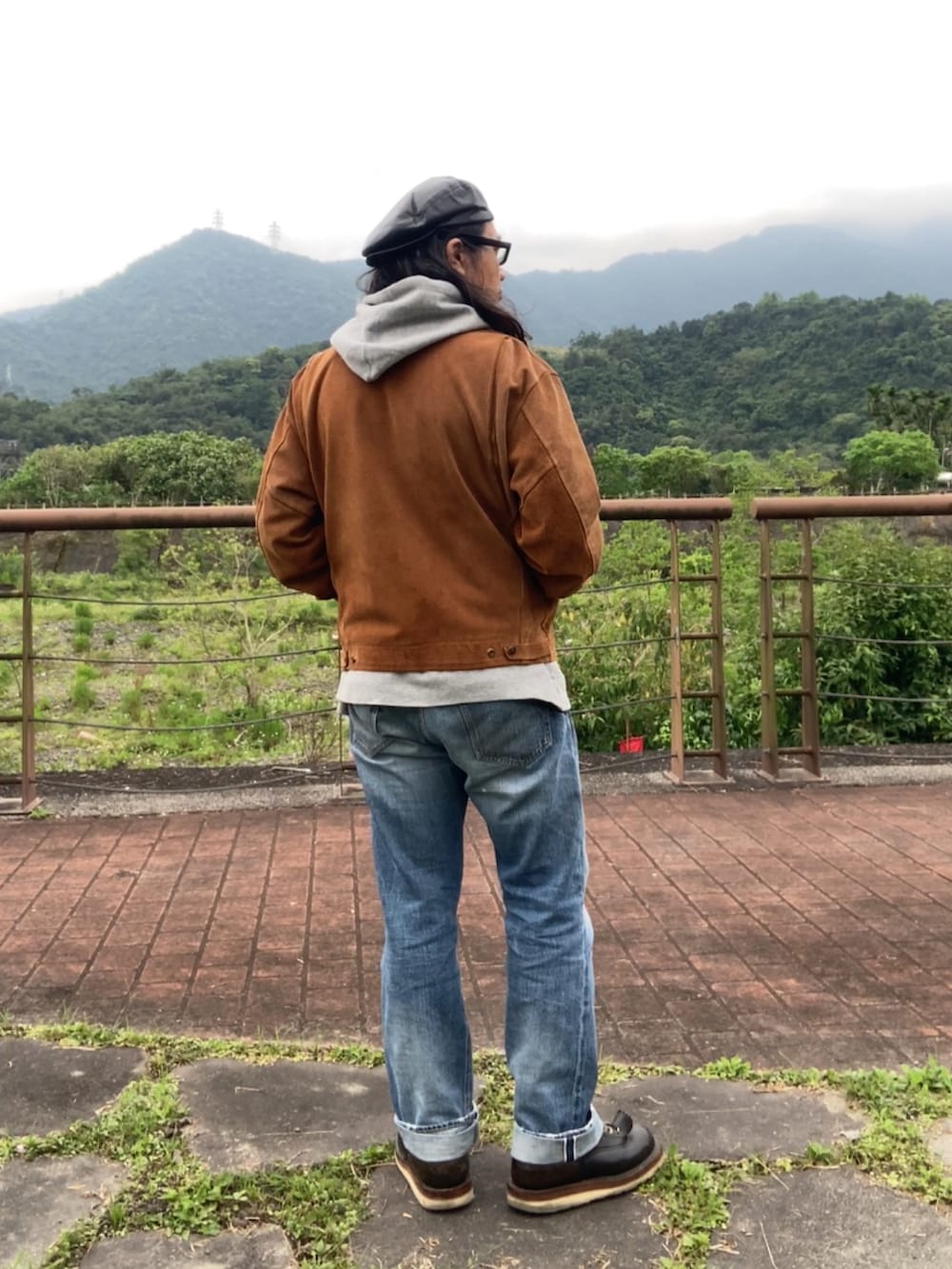 ブラウン系のその他アウター、ブラック系のブーツ、グレー系のパーカーを着用したメンズの春コーディネートの3枚目の写真