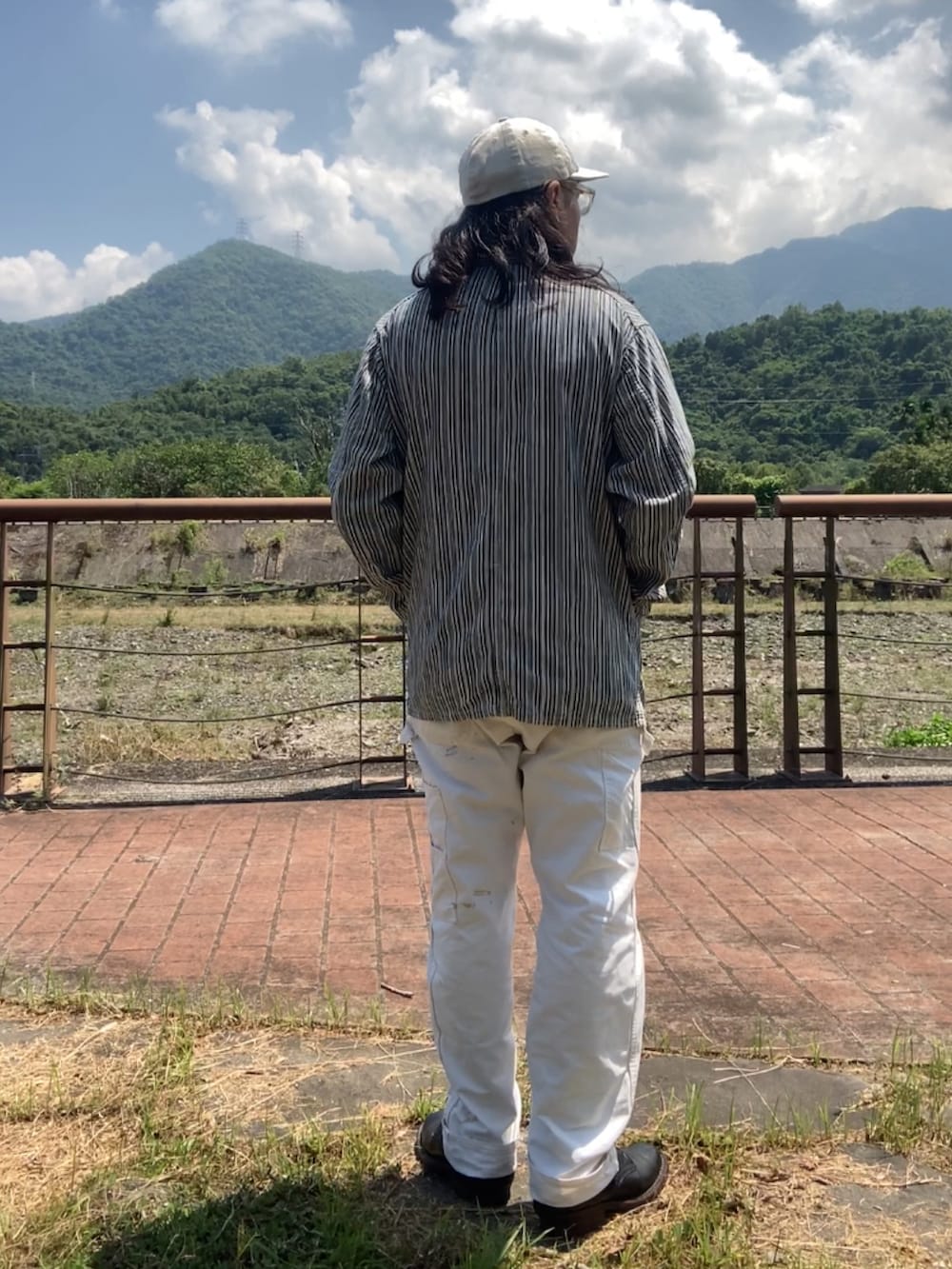 ブラック系のブーツ、ベージュ系のカバーオール、グレー系のTシャツ/カットソーを着用したメンズの夏コーディネートの2枚目の写真