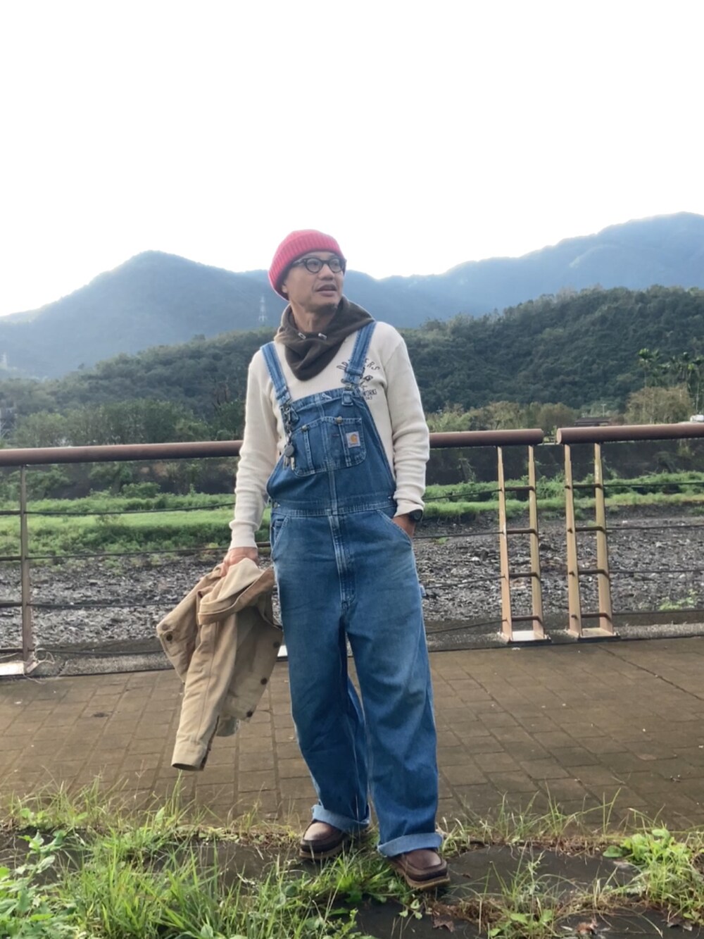 ベージュ系のデニムジャケット、ブルー系のサロペット/オーバーオール、ブラウン系のブーツを着用したメンズの冬コーディネートの3枚目の写真