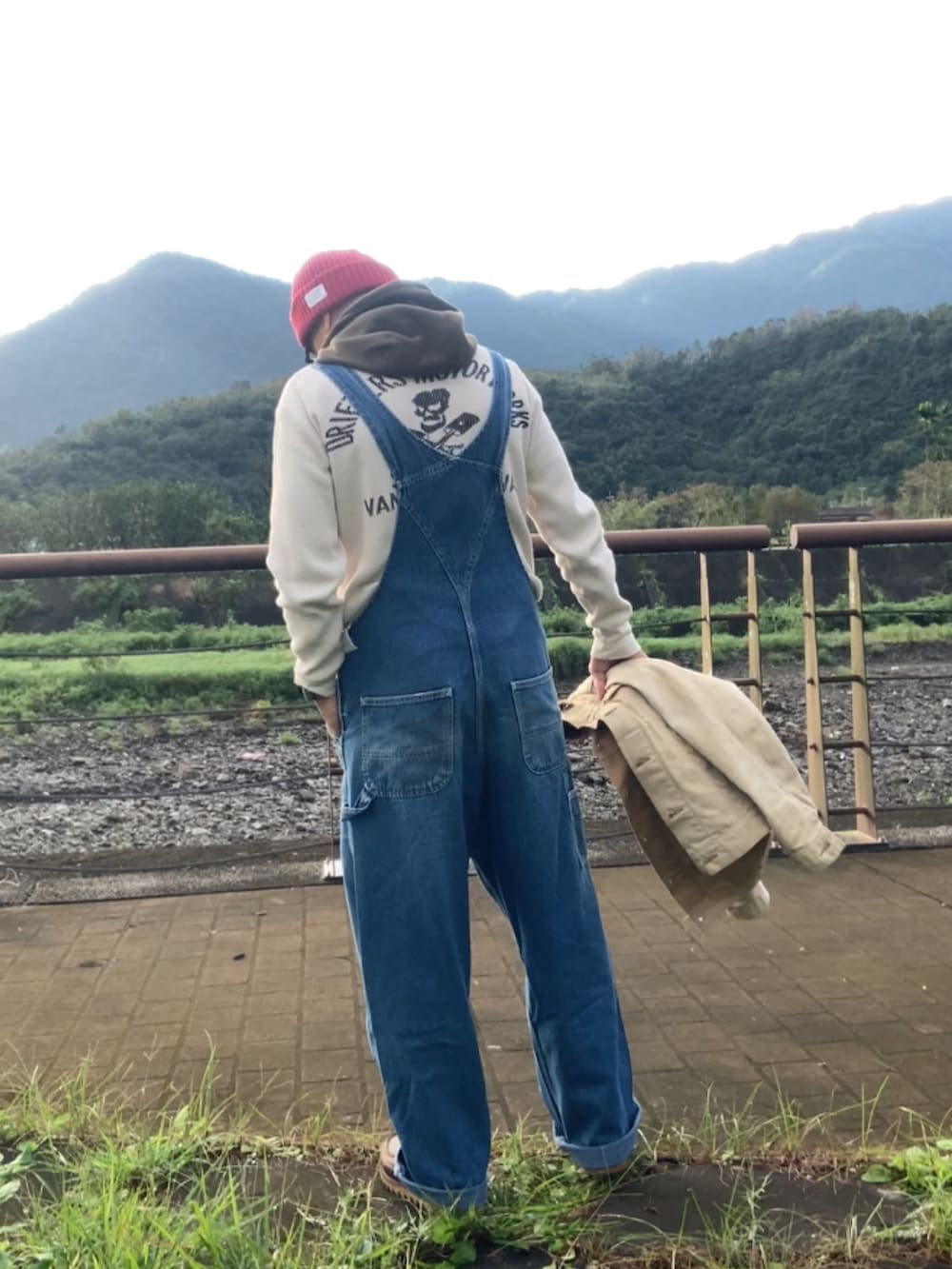 ベージュ系のデニムジャケット、ブルー系のサロペット/オーバーオール、ブラウン系のブーツを着用したメンズの冬コーディネートの2枚目の写真