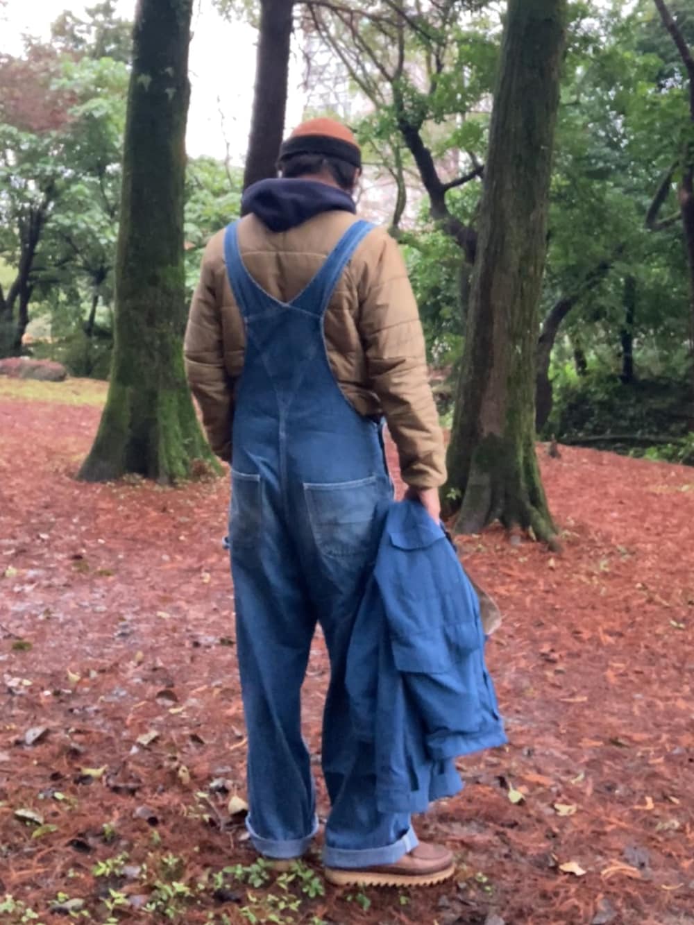 ブルー系のサロペット/オーバーオール、ブルー系のマウンテンパーカー、ブラウン系のブーツを着用したメンズの冬コーディネートの3枚目の写真