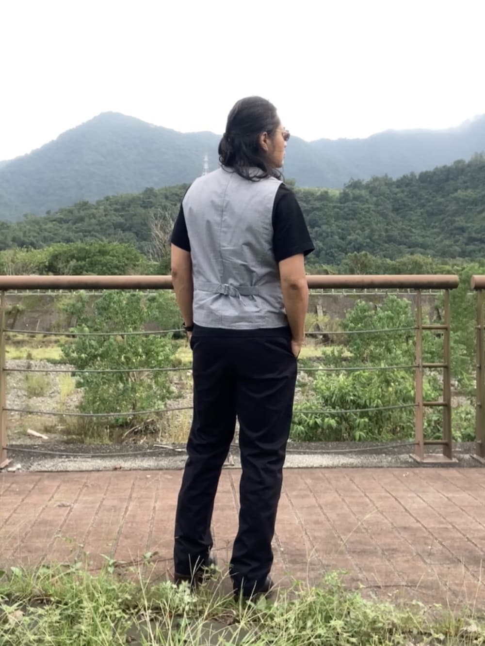 ブラック系のチノパンツ、ブラック系のブーツ、グレー系のベストを着用したメンズの秋コーディネートの4枚目の写真