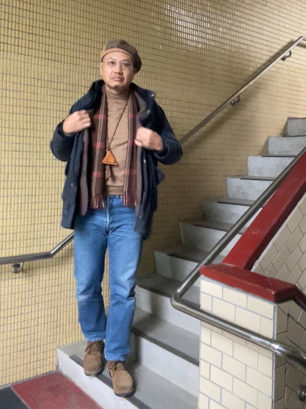 ブラウン系のテーラードジャケット、ブラウン系のニット/セーター、ブルー系のデニムパンツを着用したメンズの冬コーディネートの2枚目の写真