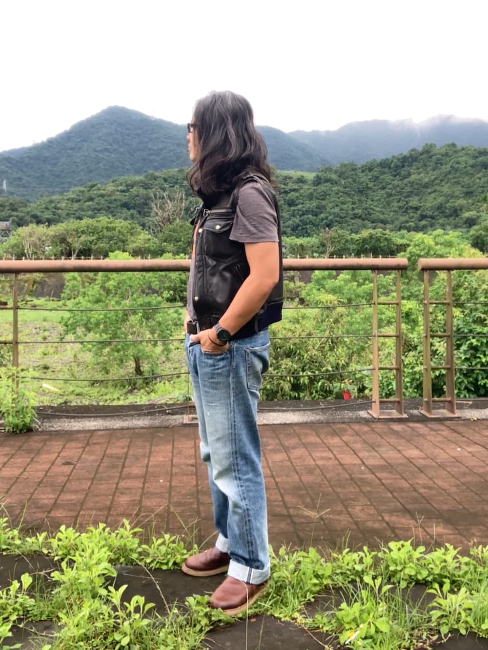 ブラウン系のスリッポン、ブルー系のデニムパンツ、ブラック系のミリタリージャケットを着用したメンズの夏コーディネートの3枚目の写真