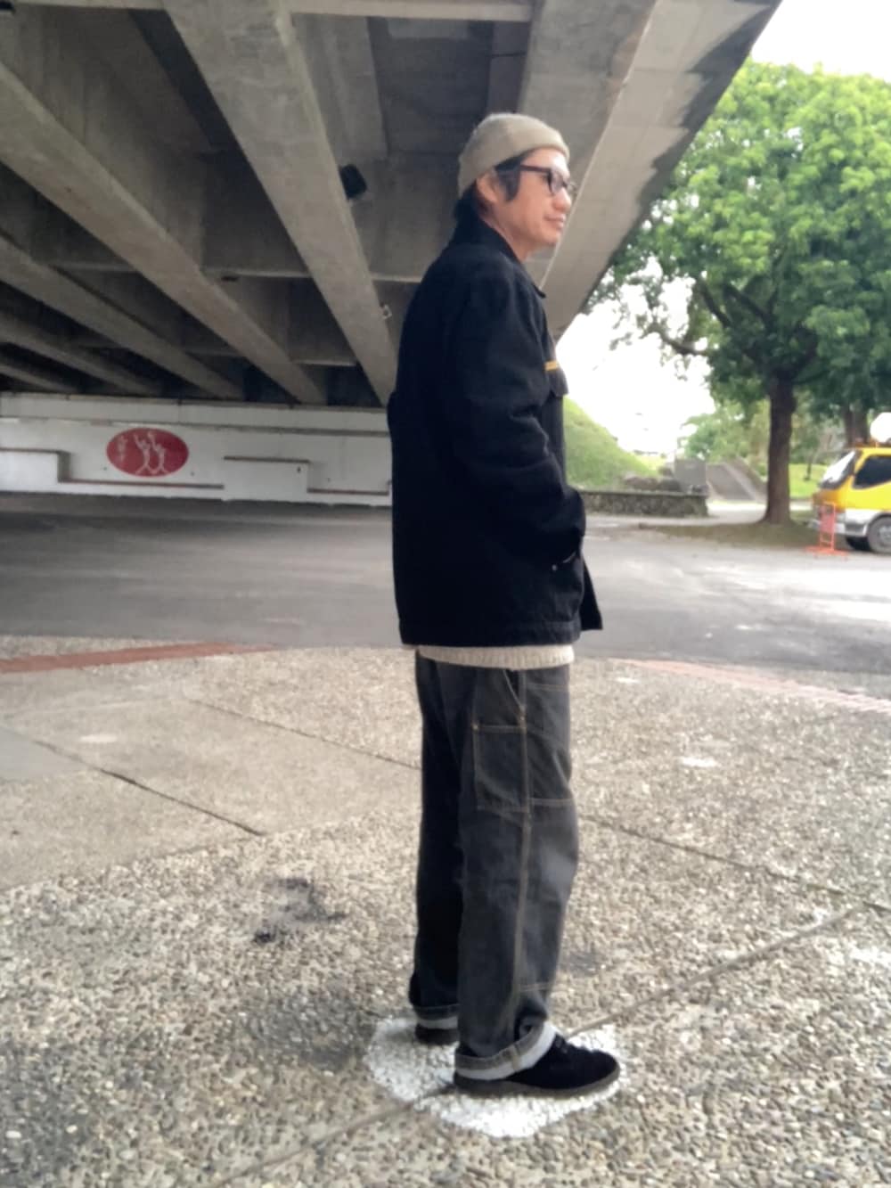 ブラック系のカバーオール、ベージュ系のニット/セーター、ブラック系のデニムパンツを着用したメンズの冬コーディネートの2枚目の写真