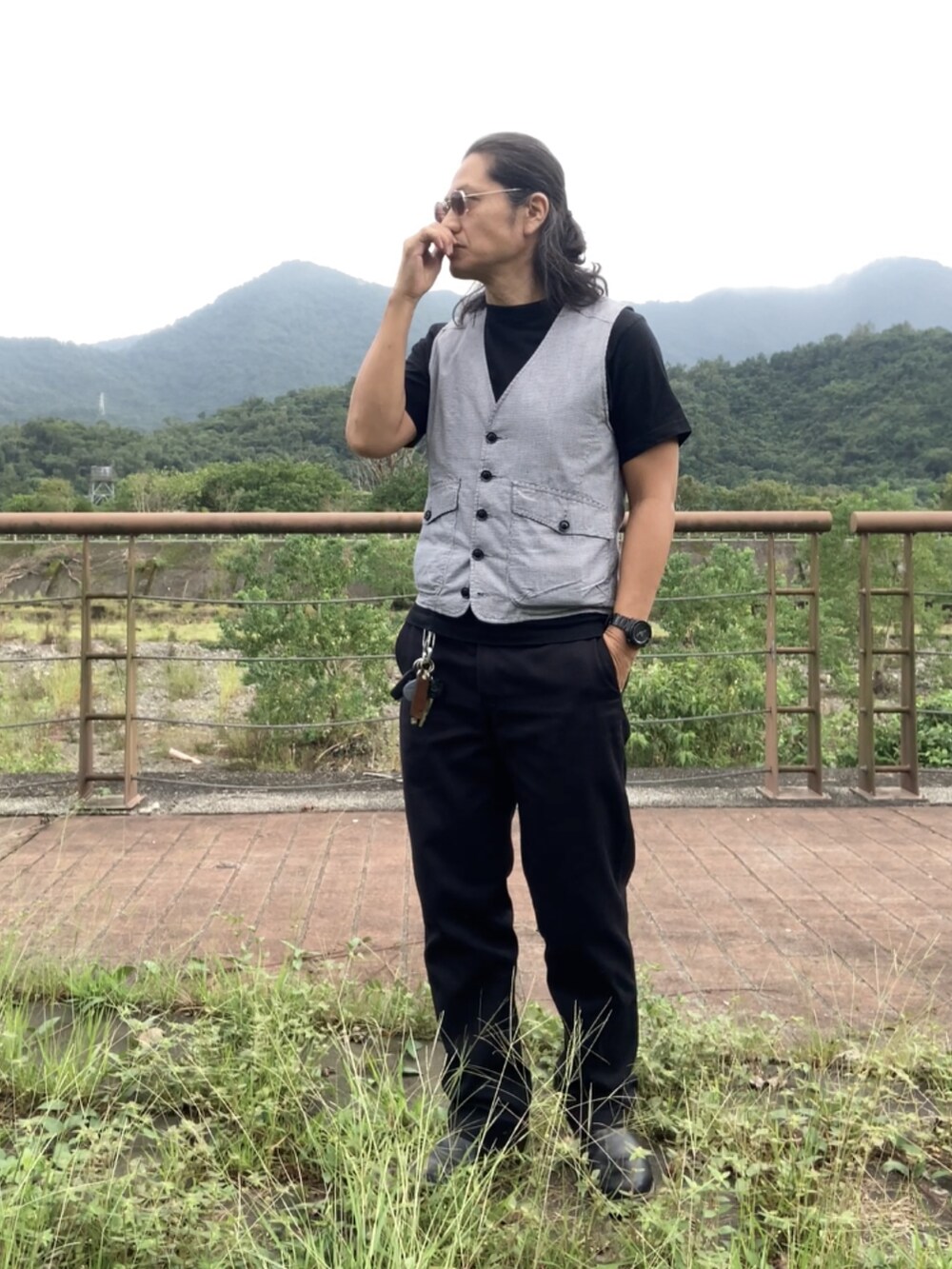 ブラック系のチノパンツ、ブラック系のブーツ、グレー系のベストを着用したメンズの秋コーディネートの3枚目の写真