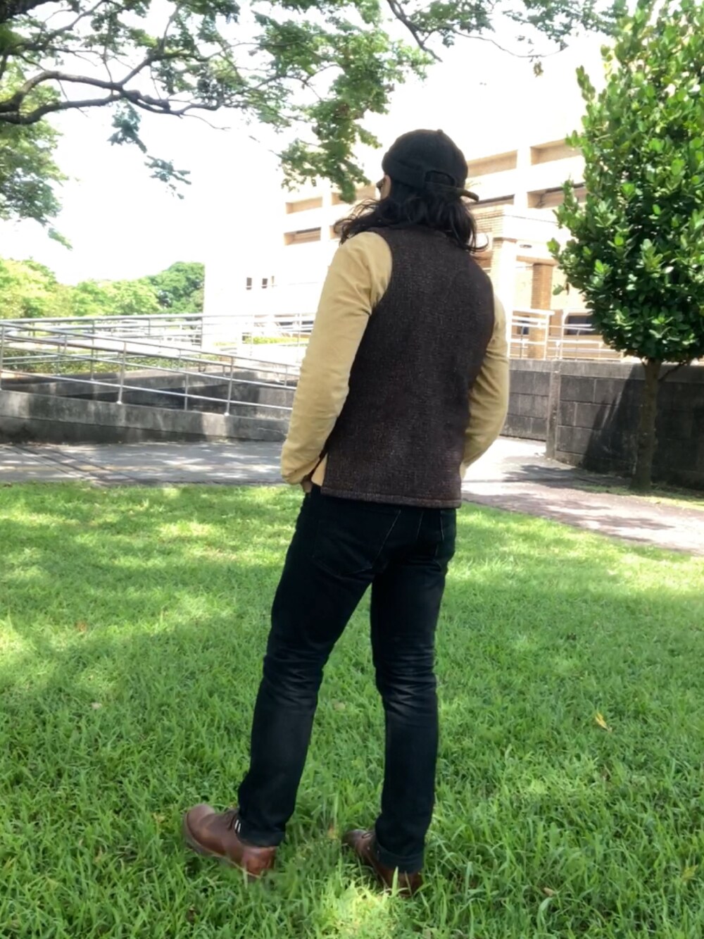 ブラウン系のベスト、ブラック系のデニムパンツ、ブラウン系のその他シューズを着用したメンズの春コーディネートの2枚目の写真