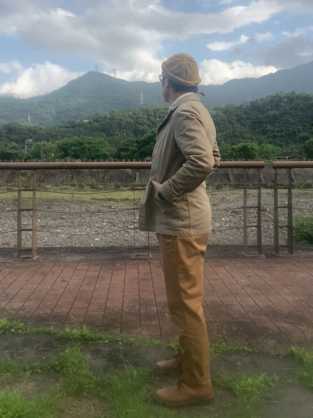 ベージュ系のカバーオール、ブラウン系のチノパンツ、ブラウン系のブーツを着用したメンズの春コーディネートの3枚目の写真