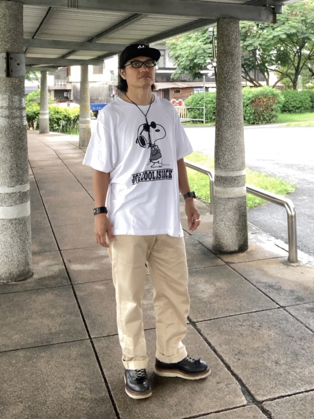 ホワイト系のTシャツ/カットソー、ベージュ系のチノパンツ、ブラック系のブーツを着用したメンズの夏コーディネートの2枚目の写真