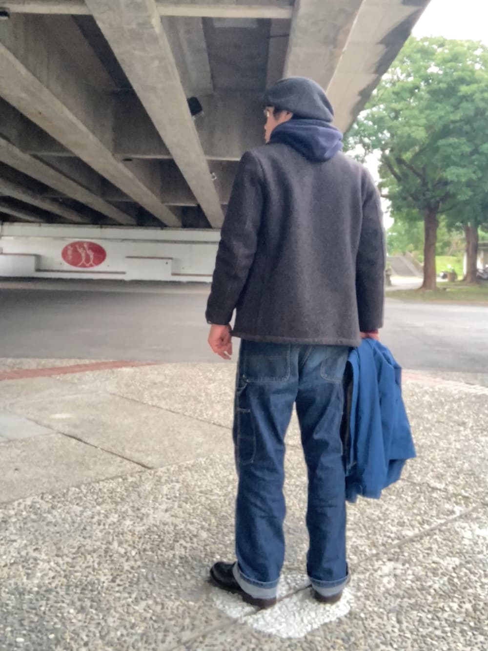 グレー系のピーコート、ブルー系のパーカー、ブルー系のデニムパンツを着用したメンズの冬コーディネートの3枚目の写真
