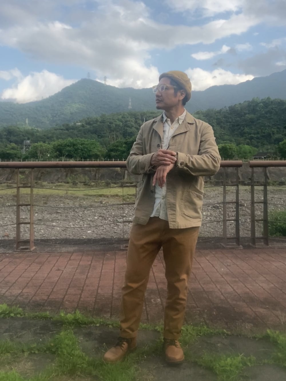 ベージュ系のカバーオール、ブラウン系のチノパンツ、ブラウン系のブーツを着用したメンズの春コーディネートの2枚目の写真