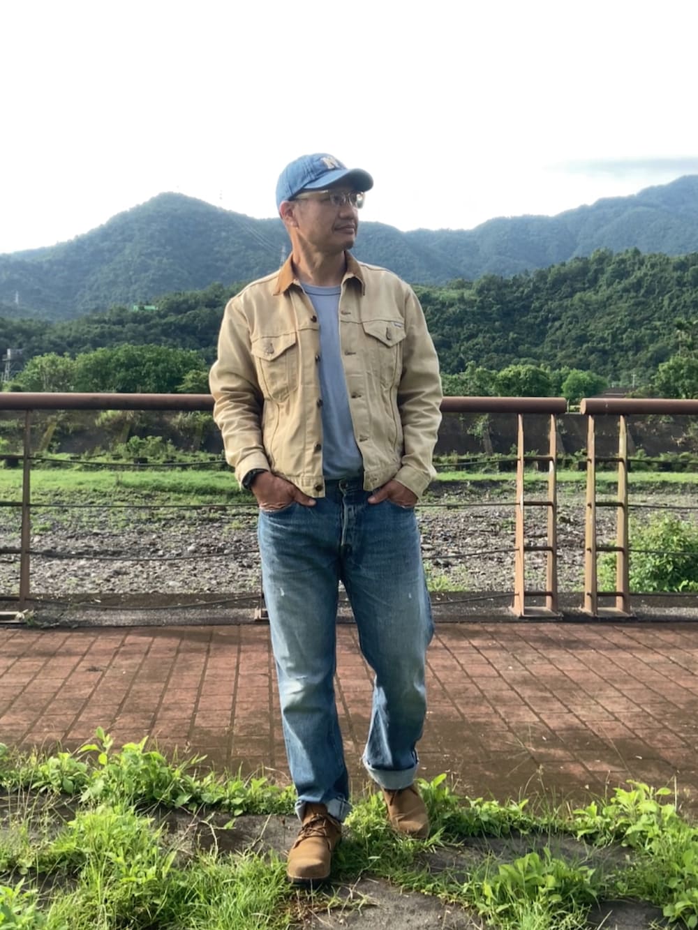 ベージュ系のデニムジャケット、ブルー系のデニムパンツ、ブラウン系のブーツを着用したメンズの春コーディネートの2枚目の写真