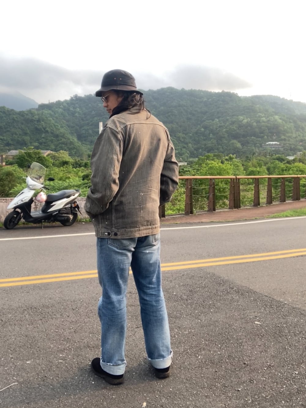 ブラック系のデニムジャケット、ブラウン系のTシャツ/カットソー、ブルー系のデニムパンツを着用したメンズの春コーディネートの3枚目の写真