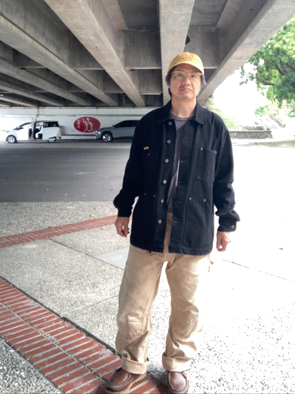 ブラック系のカバーオール、ベージュ系のその他パンツ、ブラウン系のブーツを着用したメンズの冬コーディネートの2枚目の写真