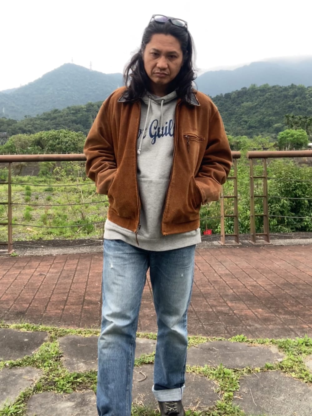 ブラウン系のその他アウター、ブルー系のデニムパンツ、ブラック系のブーツを着用したメンズの春コーディネートの2枚目の写真