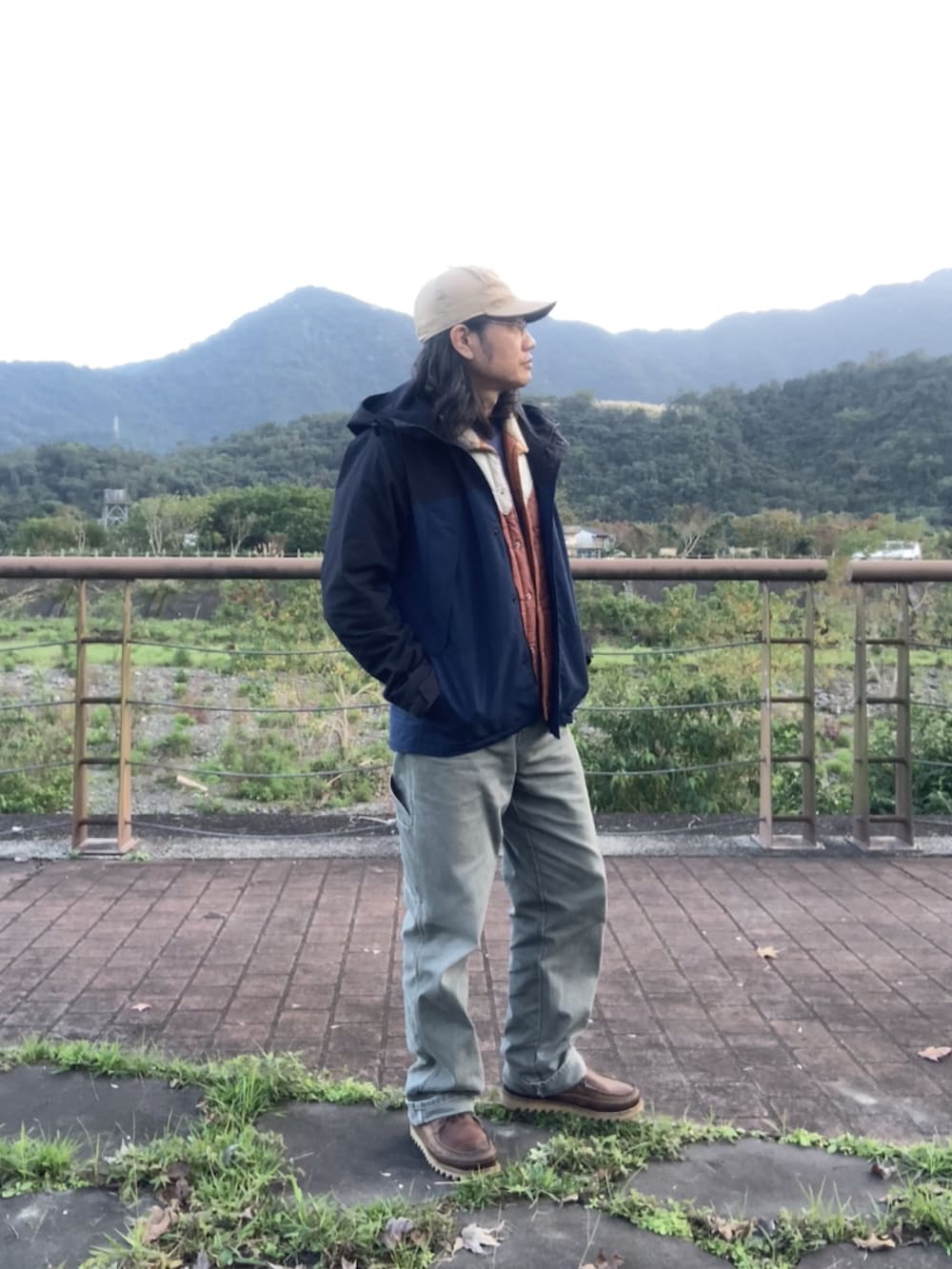 ブラウン系のブーツ、ブラック系のマウンテンパーカー、ブラウン系のベストを着用したメンズの冬コーディネートの2枚目の写真