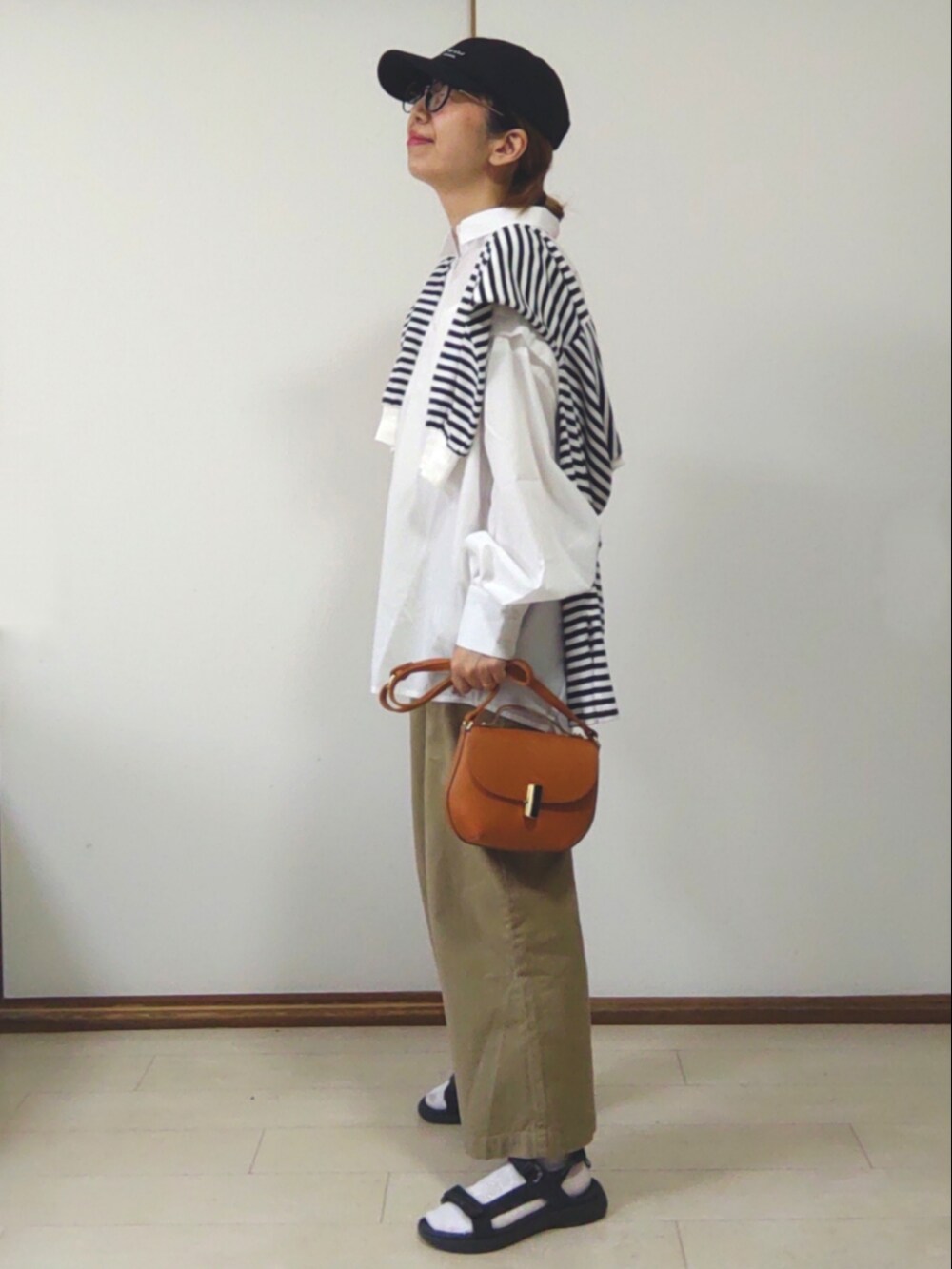 ホワイト系のシャツ/ブラウス、ブラウン系のショルダーバッグ、ベージュ系のスラックスを着用したレディースの春コーディネートの2枚目の写真