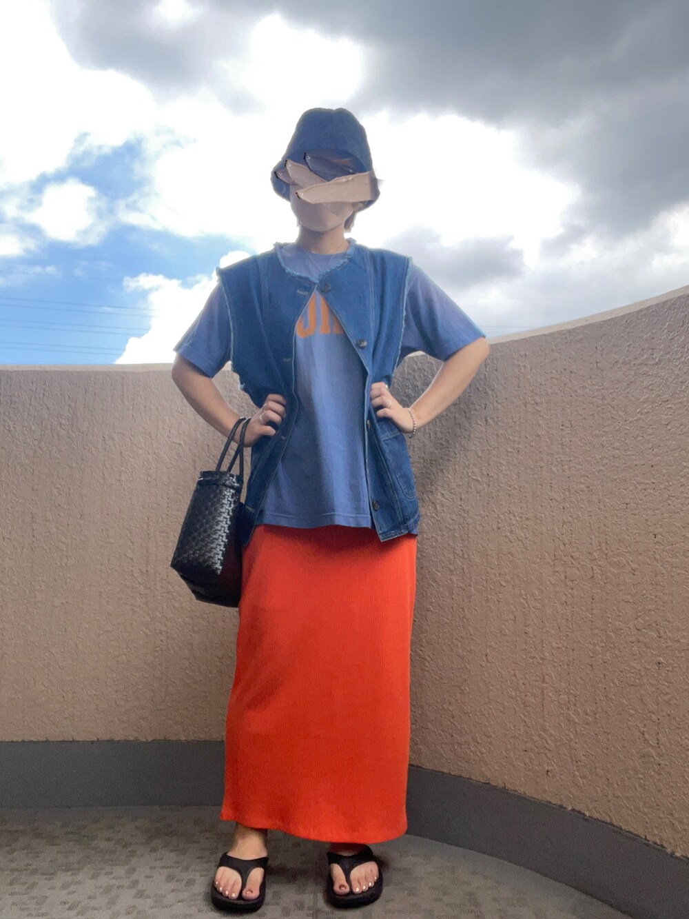 ブラック系のハンドバッグ、ブラック系のサンダル、オレンジ系のスカートを着用したレディースの夏コーディネートの2枚目の写真