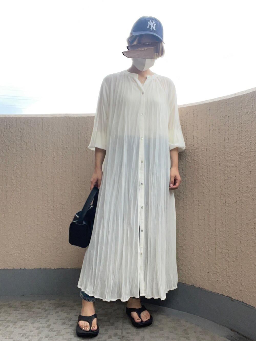 ホワイト系のワンピース、ブラック系のサンダル、ブラック系のハンドバッグを着用したレディースの夏コーディネートの4枚目の写真