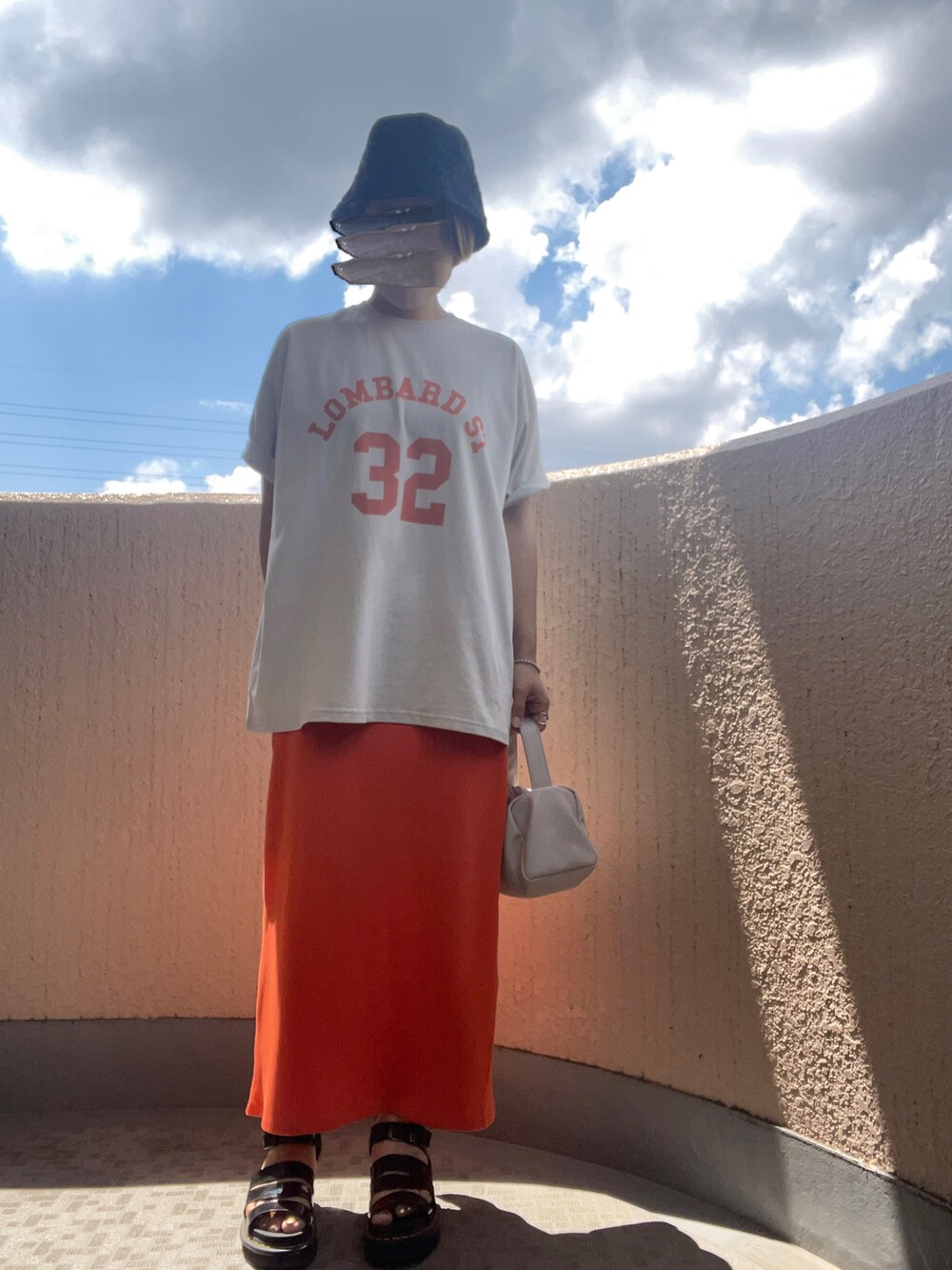 グレー系のTシャツ/カットソー、オレンジ系のスカート、ベージュ系のショルダーバッグを着用したレディースの夏コーディネートの2枚目の写真