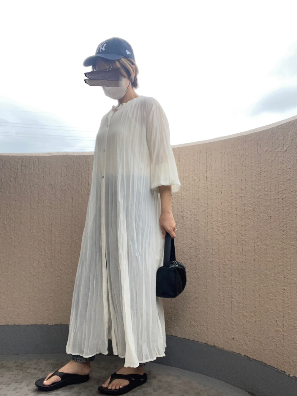 ホワイト系のワンピース、ブラック系のサンダル、ブラック系のハンドバッグを着用したレディースの夏コーディネートの3枚目の写真