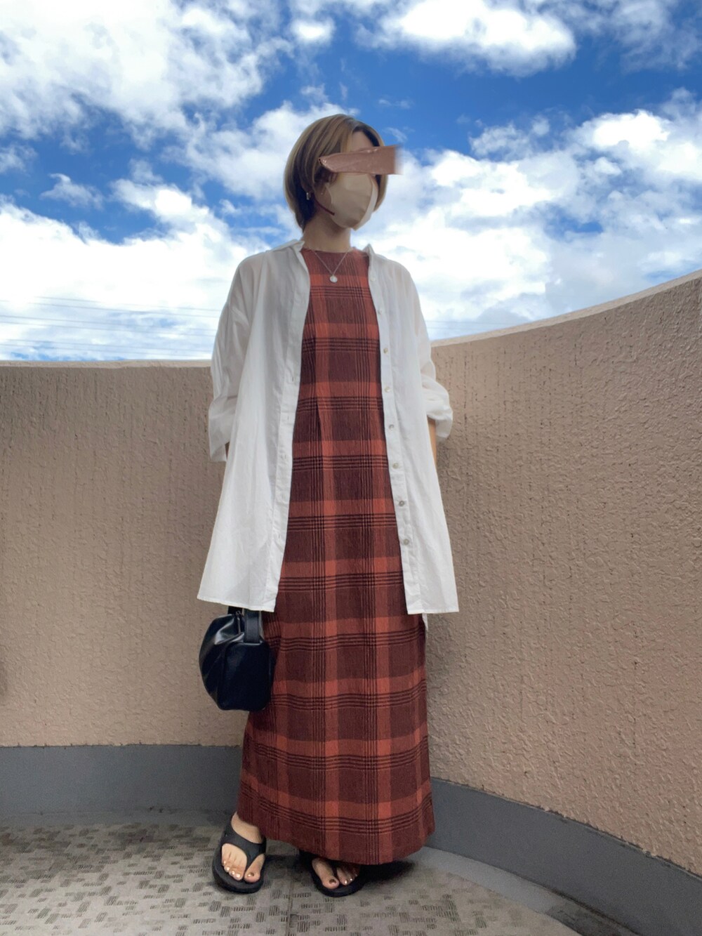 ブラック系のサンダル、オレンジ系のワンピース、ホワイト系のシャツ/ブラウスを着用したレディースの夏コーディネートの2枚目の写真