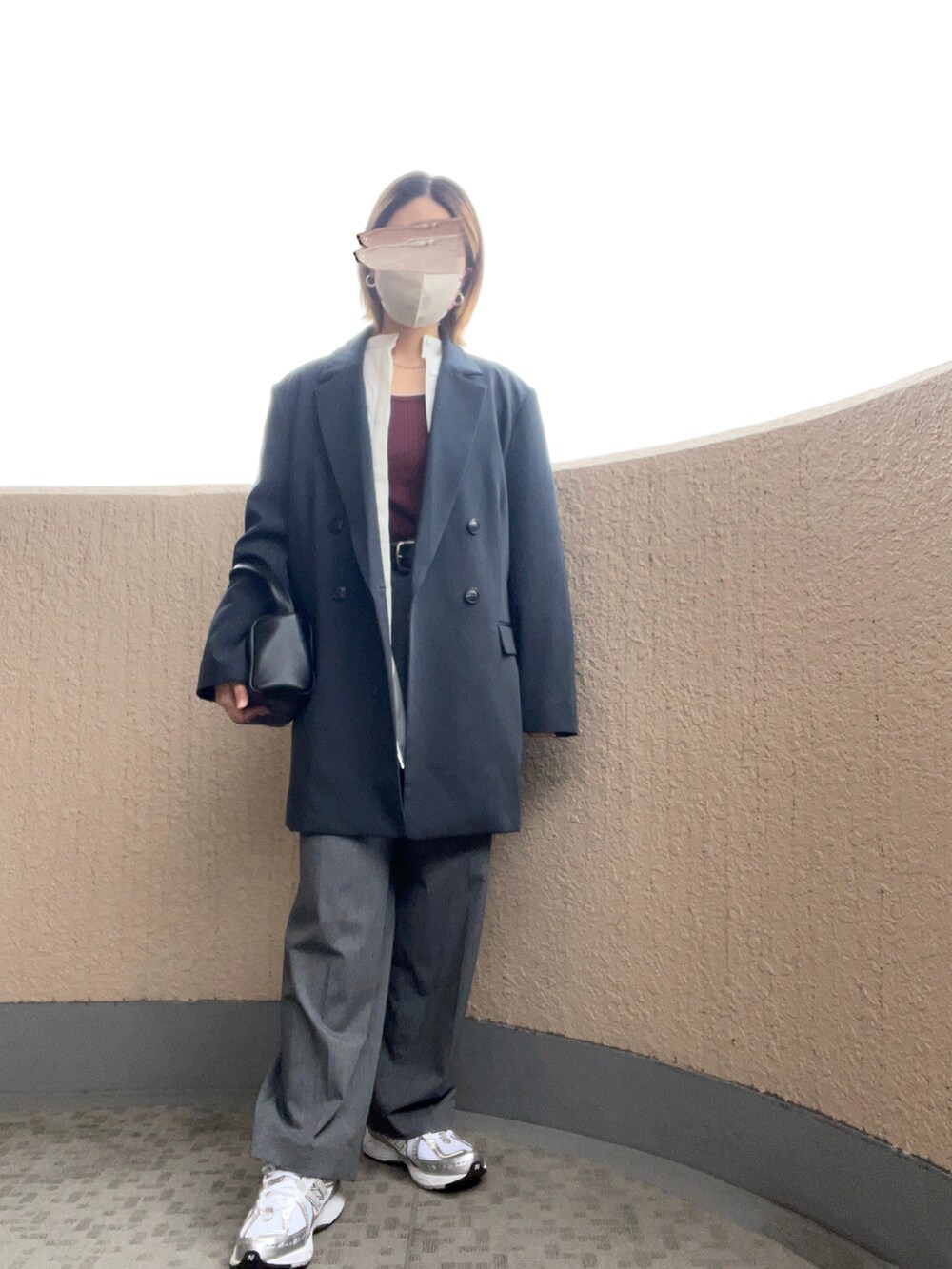 グレー系のスラックス、シルバー系のスニーカー、ブラック系のハンドバッグを着用したレディースの秋コーディネートの2枚目の写真