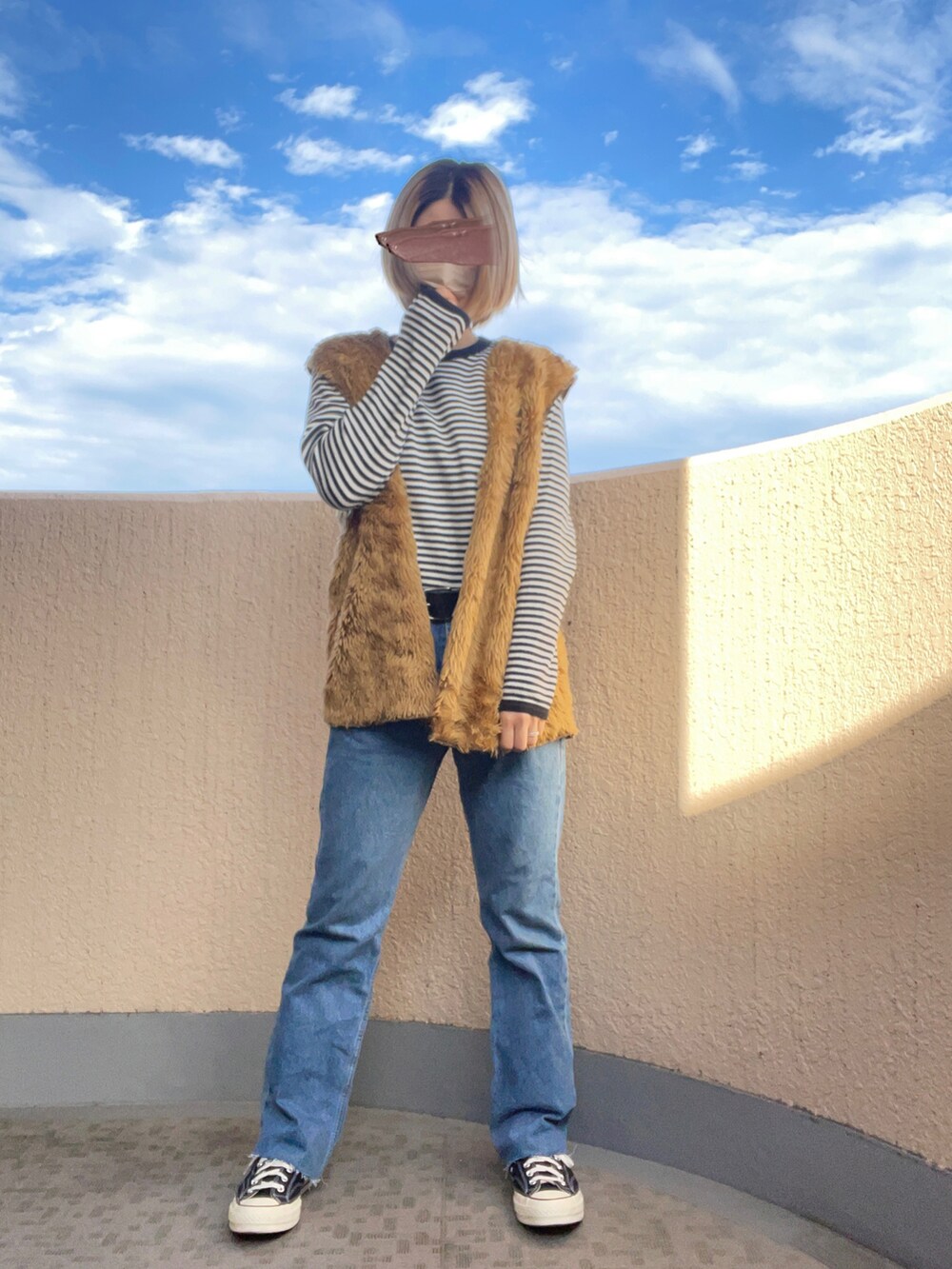 ブルー系のデニムパンツ、その他のスニーカー、ブラウン系のベストを着用したレディースの秋コーディネートの2枚目の写真