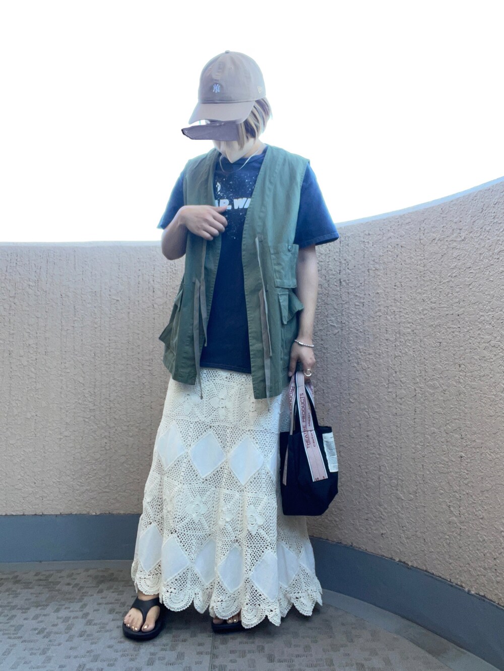 ブラック系のトートバッグ、ホワイト系のスカート、ブラック系のサンダルを着用したレディースの夏コーディネートの2枚目の写真