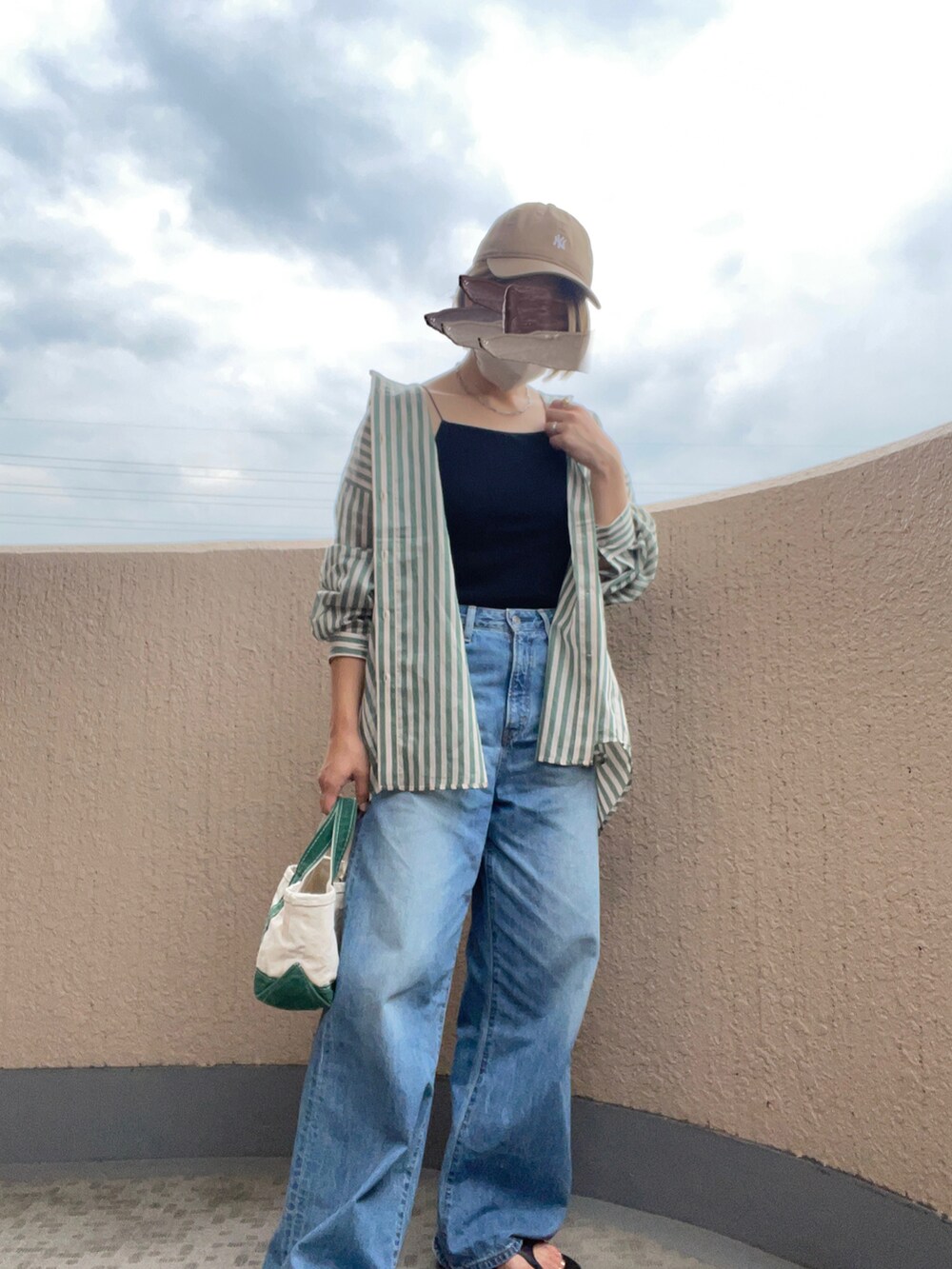 ブルー系のデニムパンツ、グリーン系のトートバッグ、ブラック系のサンダルを着用したレディースの夏コーディネートの2枚目の写真