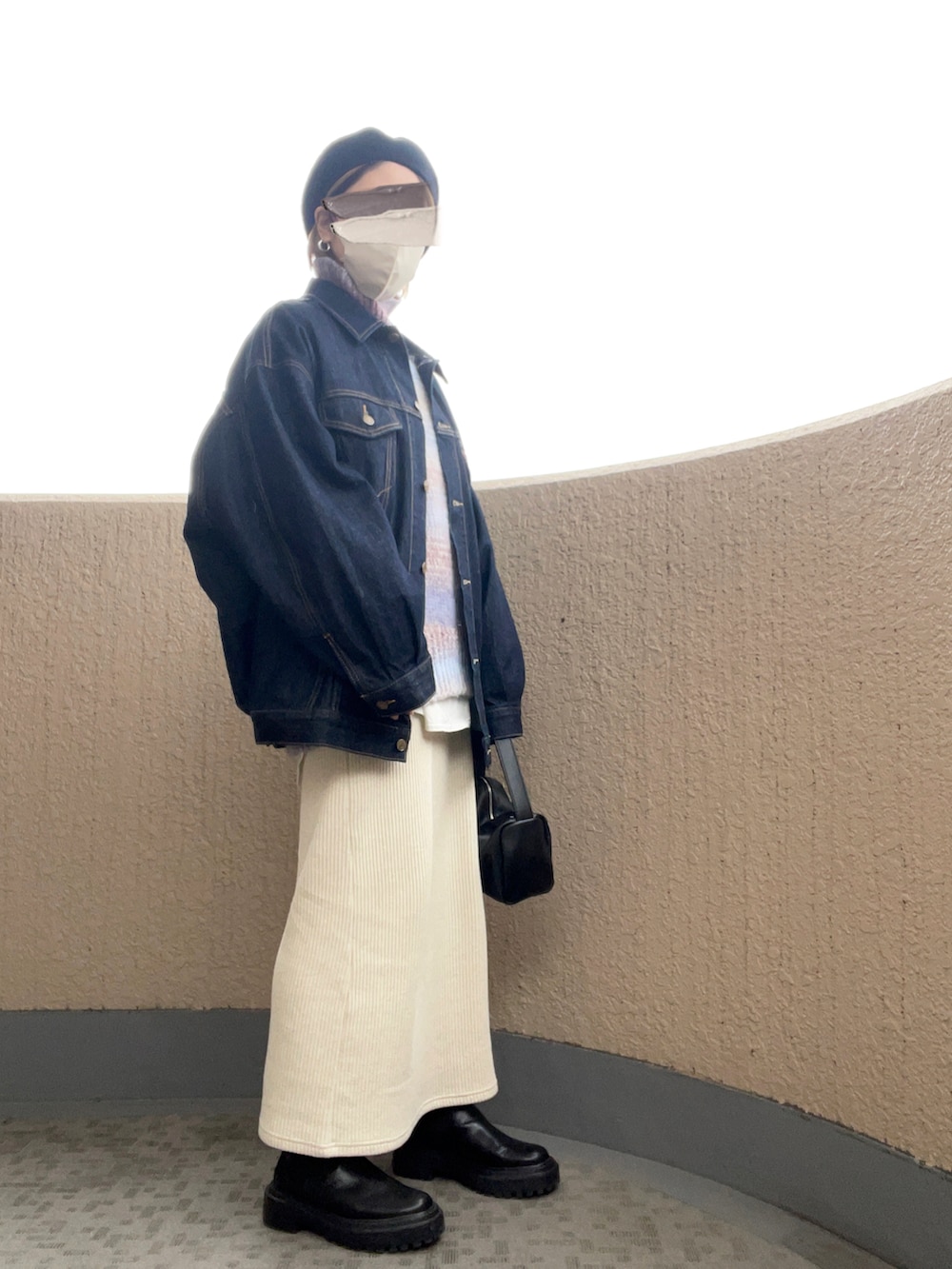 ブルー系のデニムジャケット、ブルー系のニット/セーター、ブラック系のハンドバッグを着用したレディースの秋コーディネートの2枚目の写真