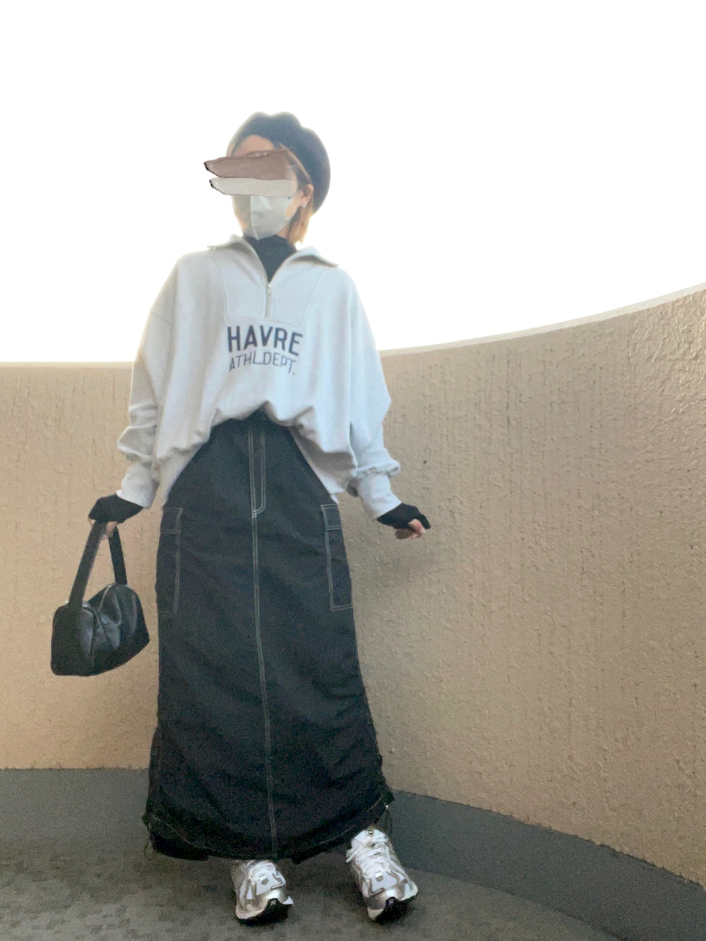 ブラック系のスカート、シルバー系のスニーカー、ブラック系のハンドバッグを着用したレディースの秋コーディネートの2枚目の写真